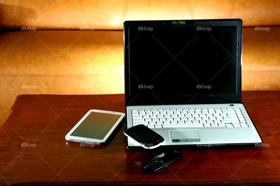 laptop computer, tablet, cellphone and a smartphone on a living room table