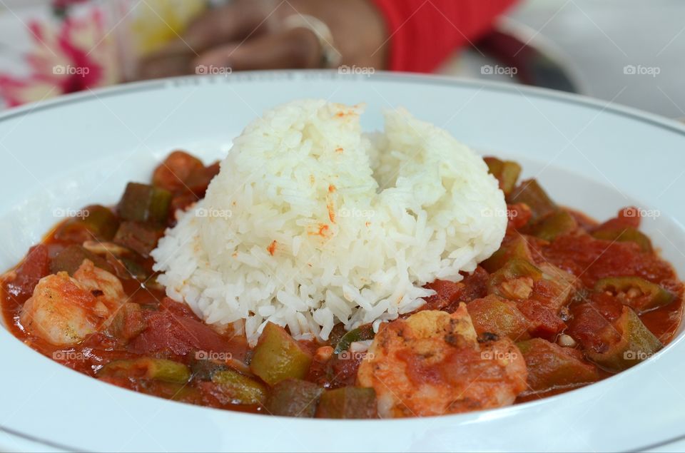 A southern patron prepares to eat a healthy prepared dish of stewed okra and tomato with jasmine rice and shrimp at an eatery in downtown historic Savannah.