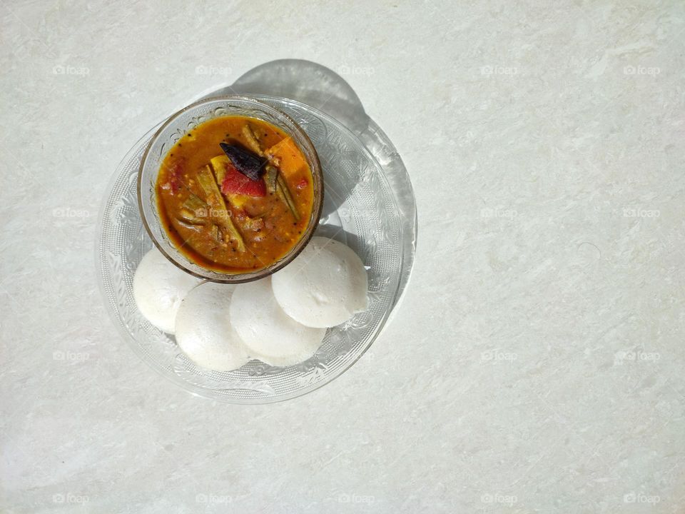 Idli and sambar, sambar a vegetable curry medium spicy, Idli is a pure white colour fluffy steamed batter consisting of fermented black lentils (de-husked) and rice