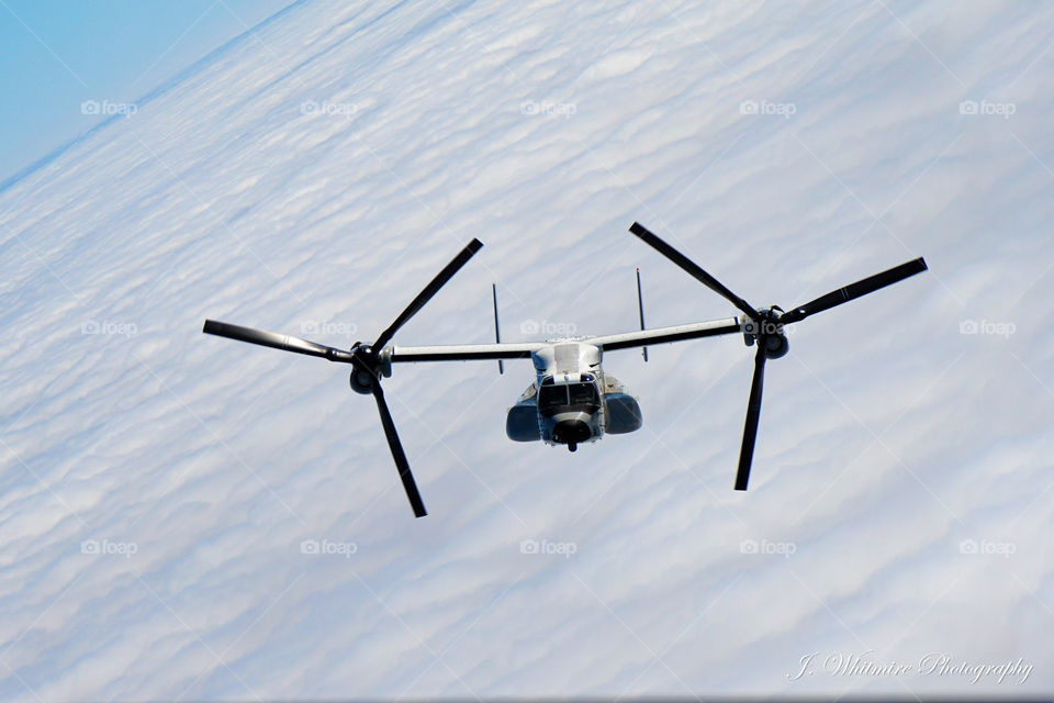 A Osprey tilt rotor craft is seen from another Osprey photographed through the open back ramp over the Pacific Ocean