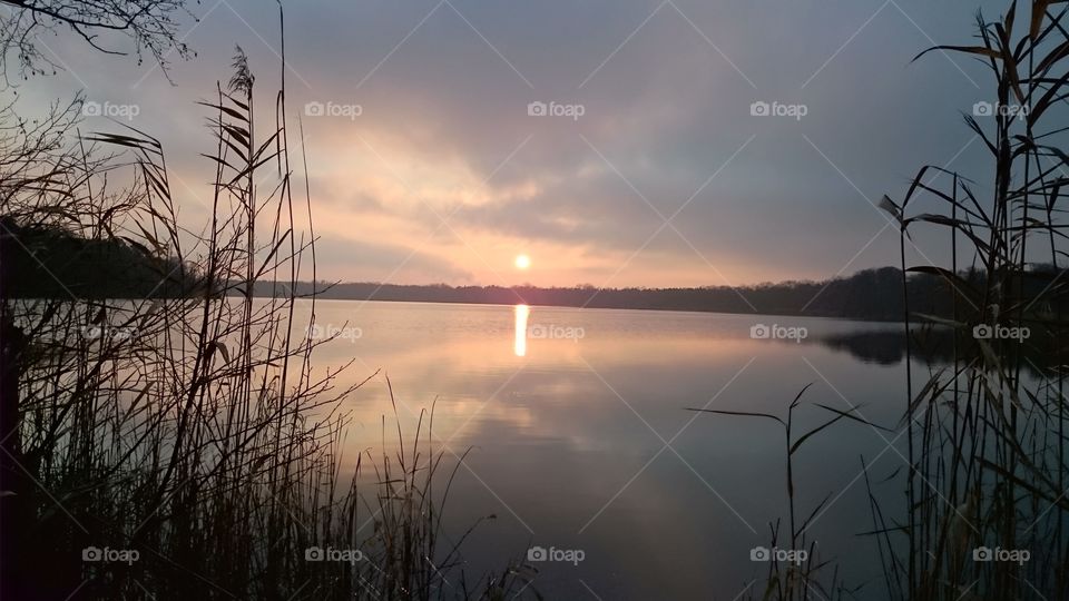 Sunset with reflecting sun and sky in the lake.