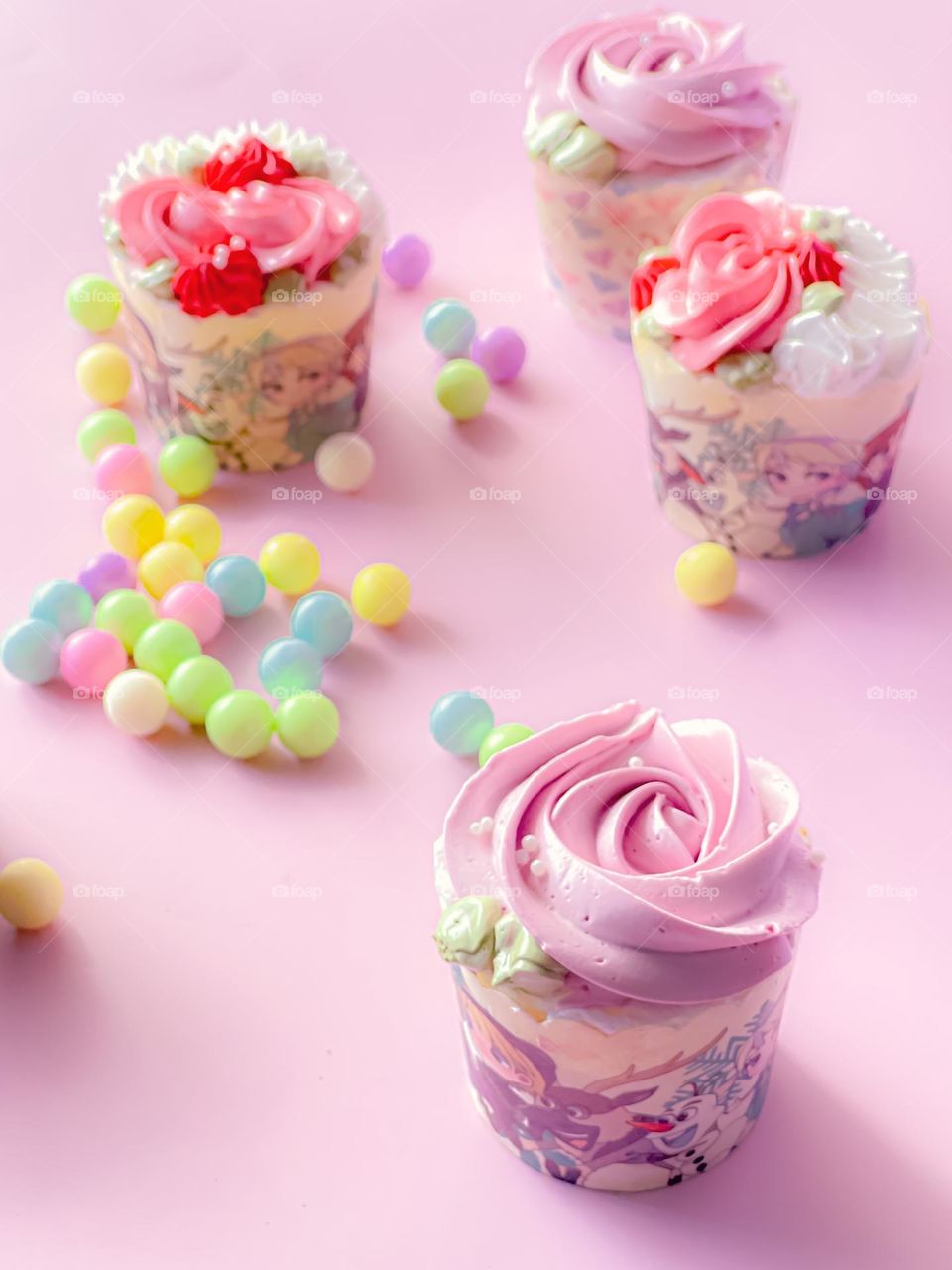 Delicious pink cupcakes with colourful candies on a pink table