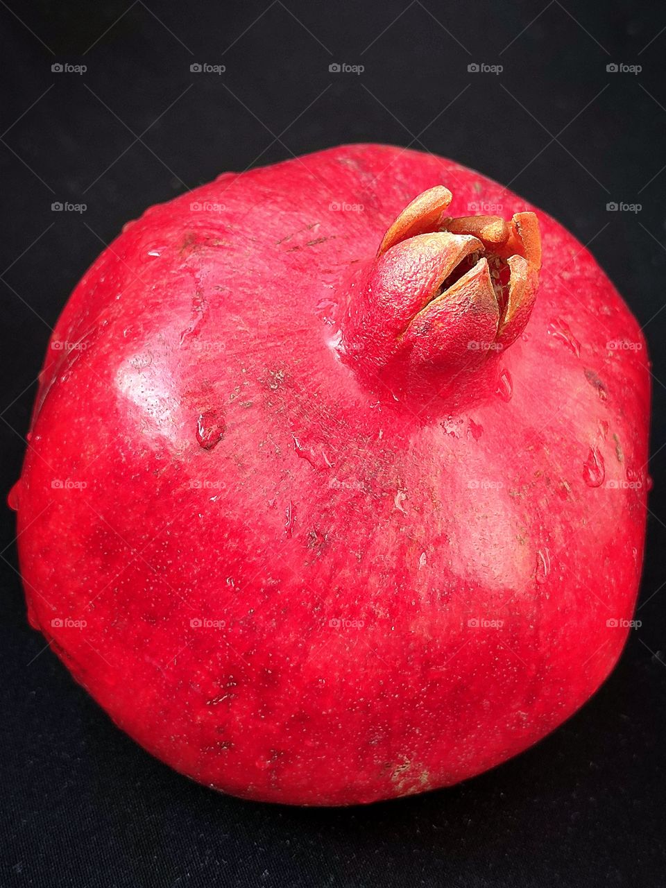 red pomegranate with water drops on black background