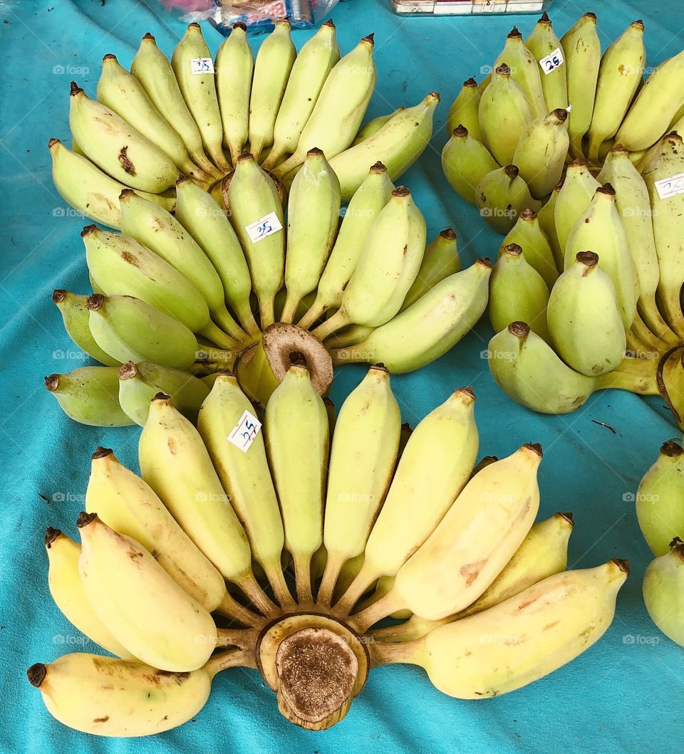 Mini little bananas bunches displayed at a fruit market on turquoise cloth, tropic fruit for sale, organic fruit 