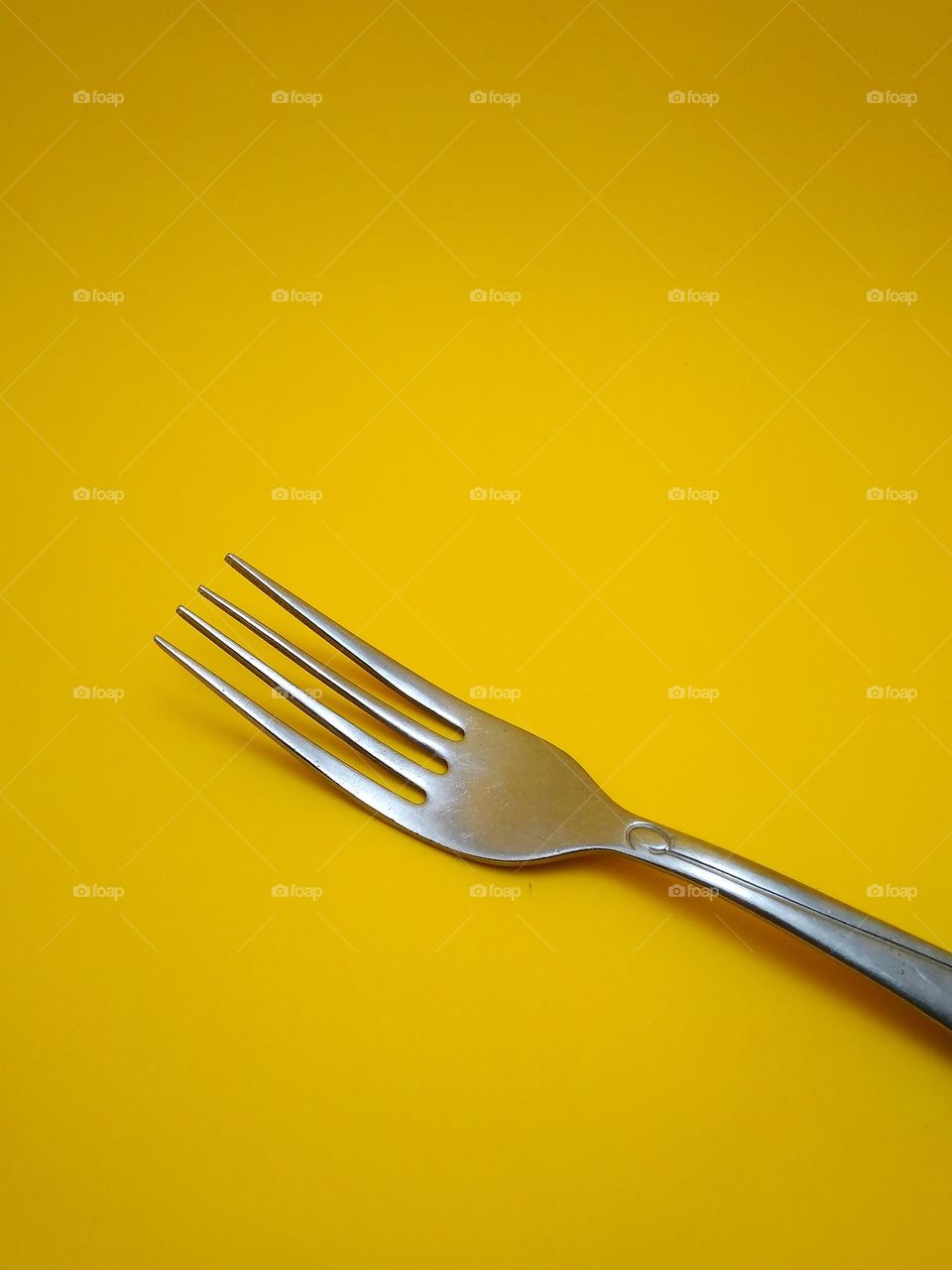 a stainless steel fork, close-up in the studio photo on a yellow background.