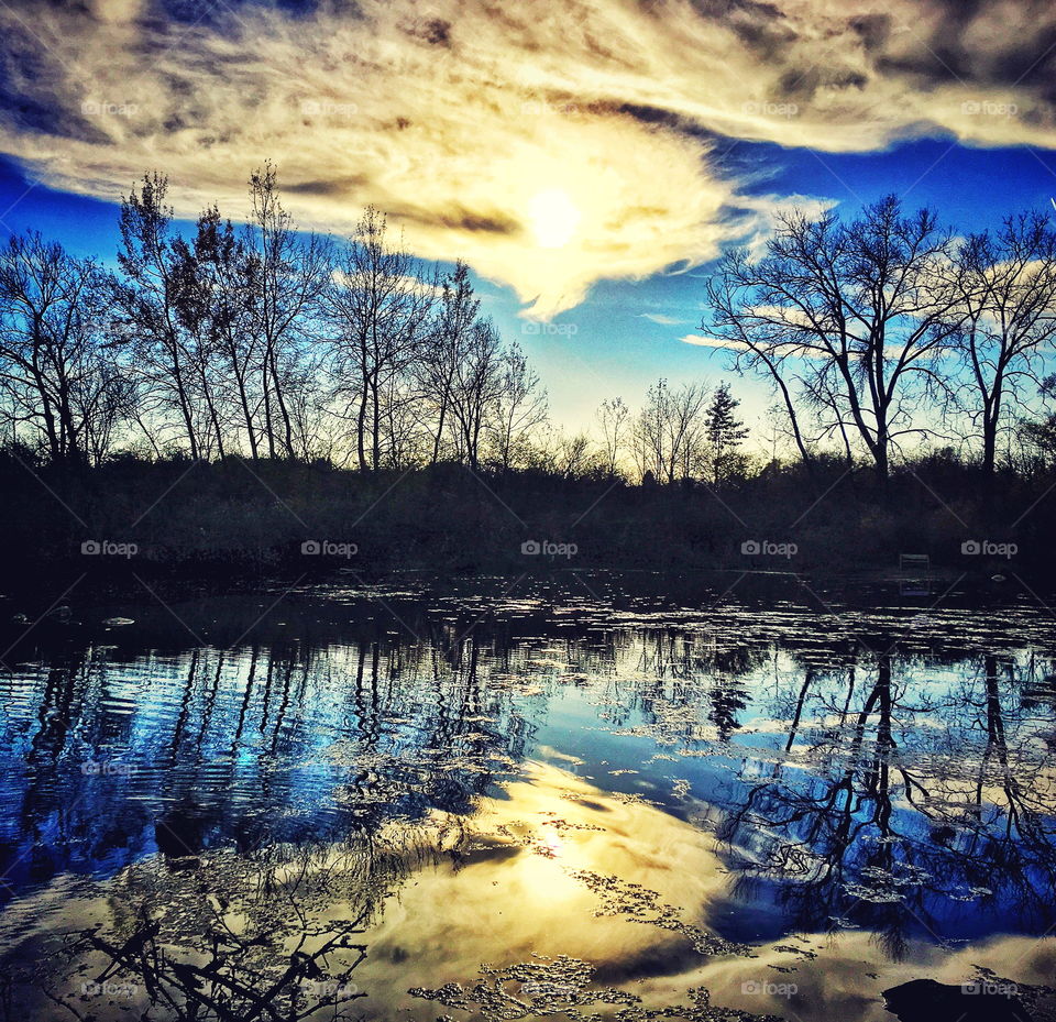 Blue sky, clouds and afternoon sunshine reflecting off the lake surface 