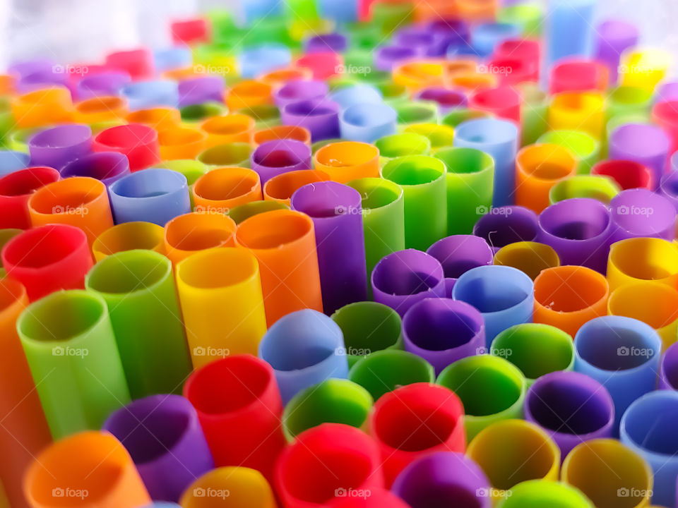 Top level view of bright rainbow colored plastic straws creating a neat circular honeycomb like design.