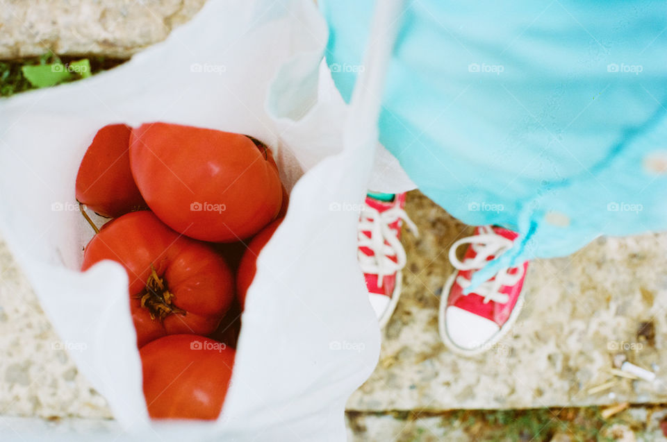 Holding food. Boy in red sneakers with tomatoes 🍅 