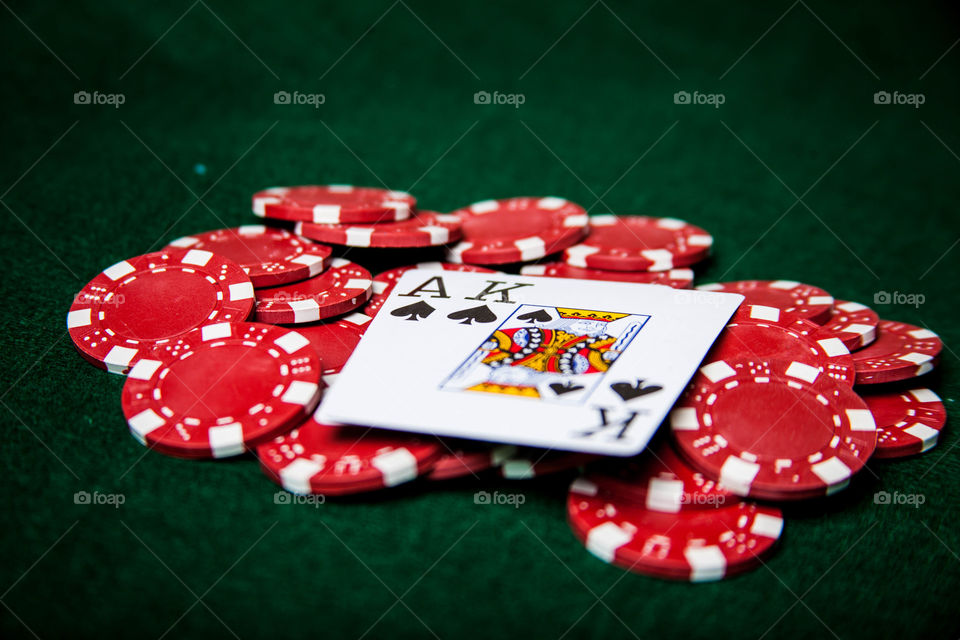 Ace and King on red poker chip. This is a photograph of red poker chips with an Ace and King of Spades on them.