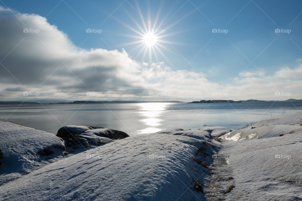 Sun shining on white snow covered cliffs by the ocean 