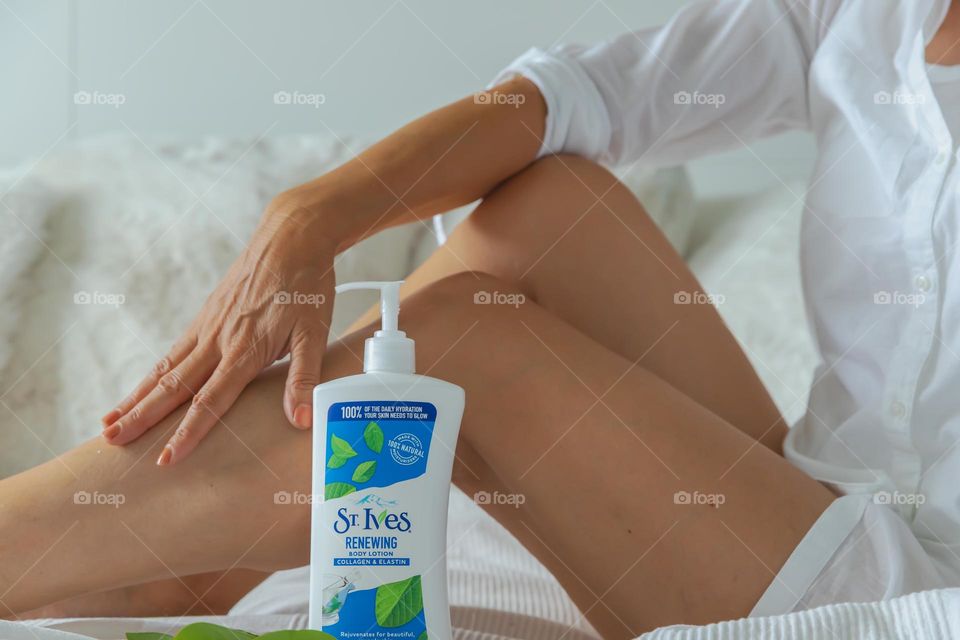 Woman applying Body Lotion on her legs 