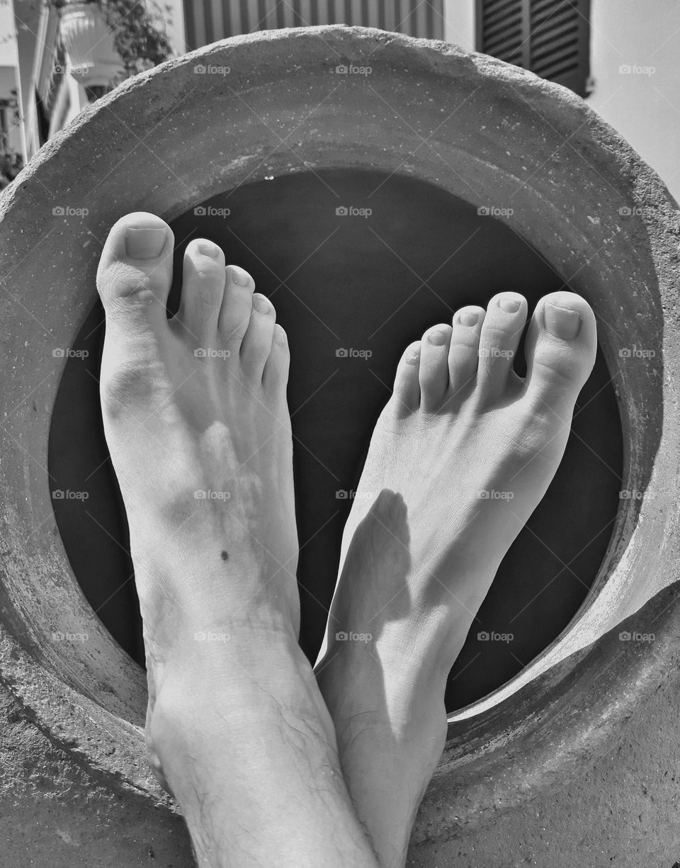 Enjoying a rest with the feet resting on the mouth of a clay jar.