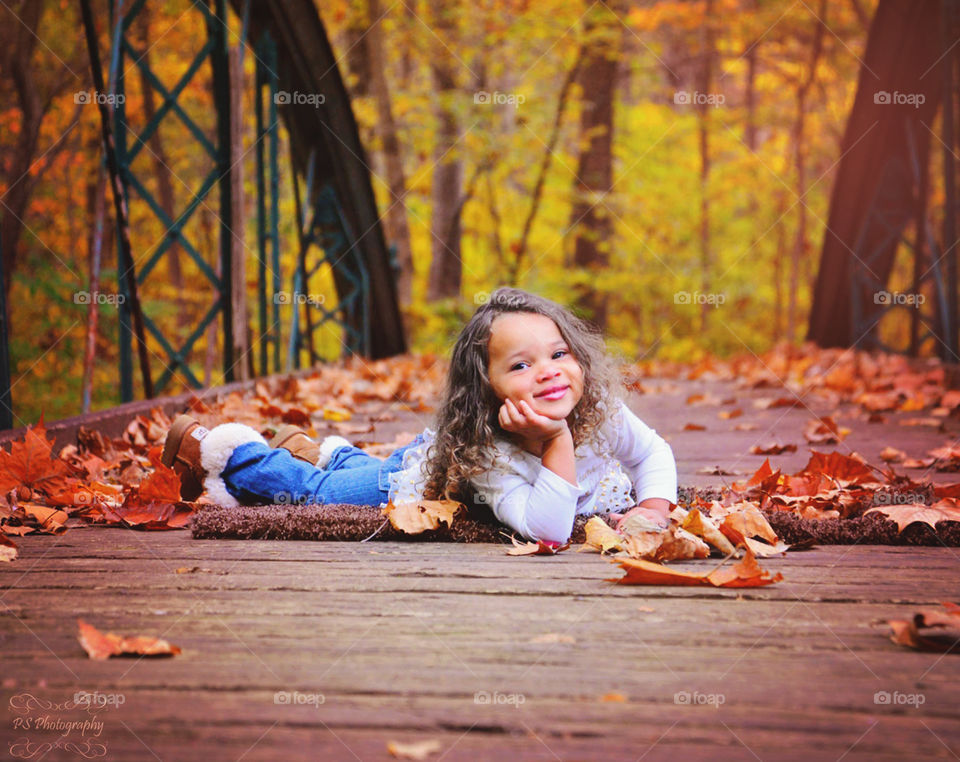 Cute girl lying on boardwalk in autumn