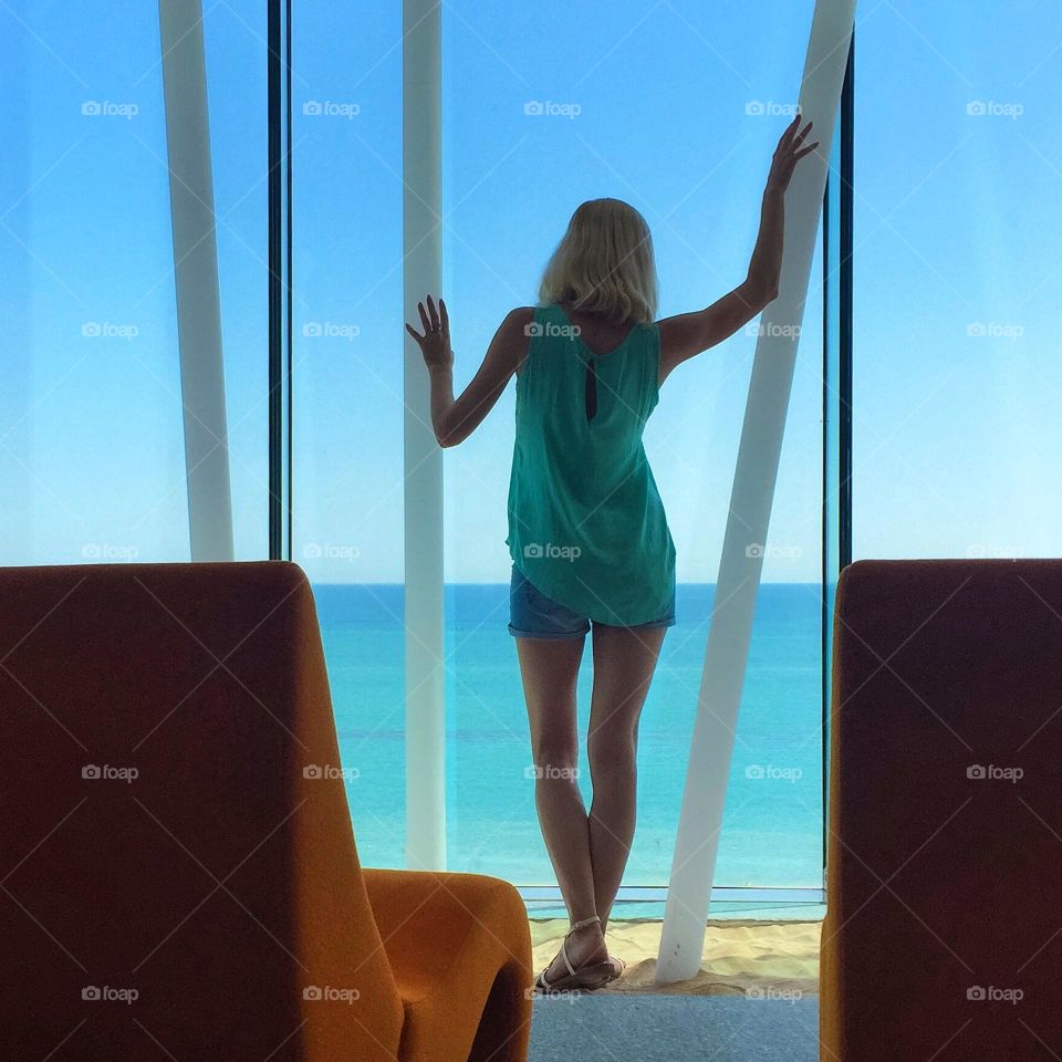 young woman standing at the window overlooking the sea