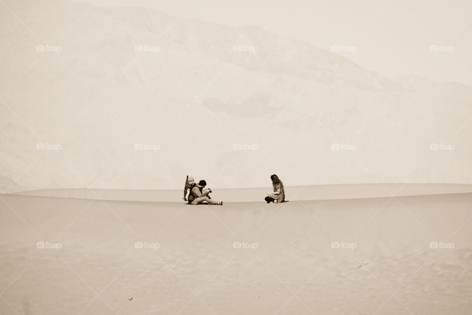 A couple sitting on sand dunes