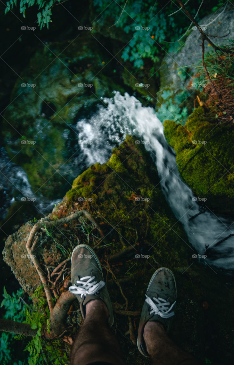 Standing on top of a waterfall in the forest.