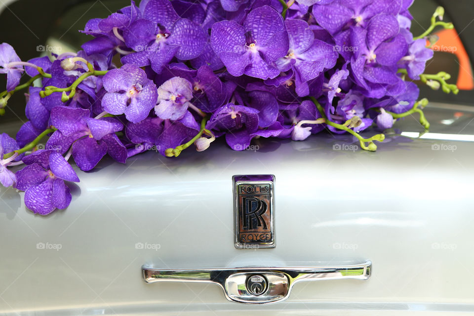 Flowers on a Rolls Royce car. Purple iris flower bouquet sits on top of a Rolls Royce luxury exotic limo car trunk