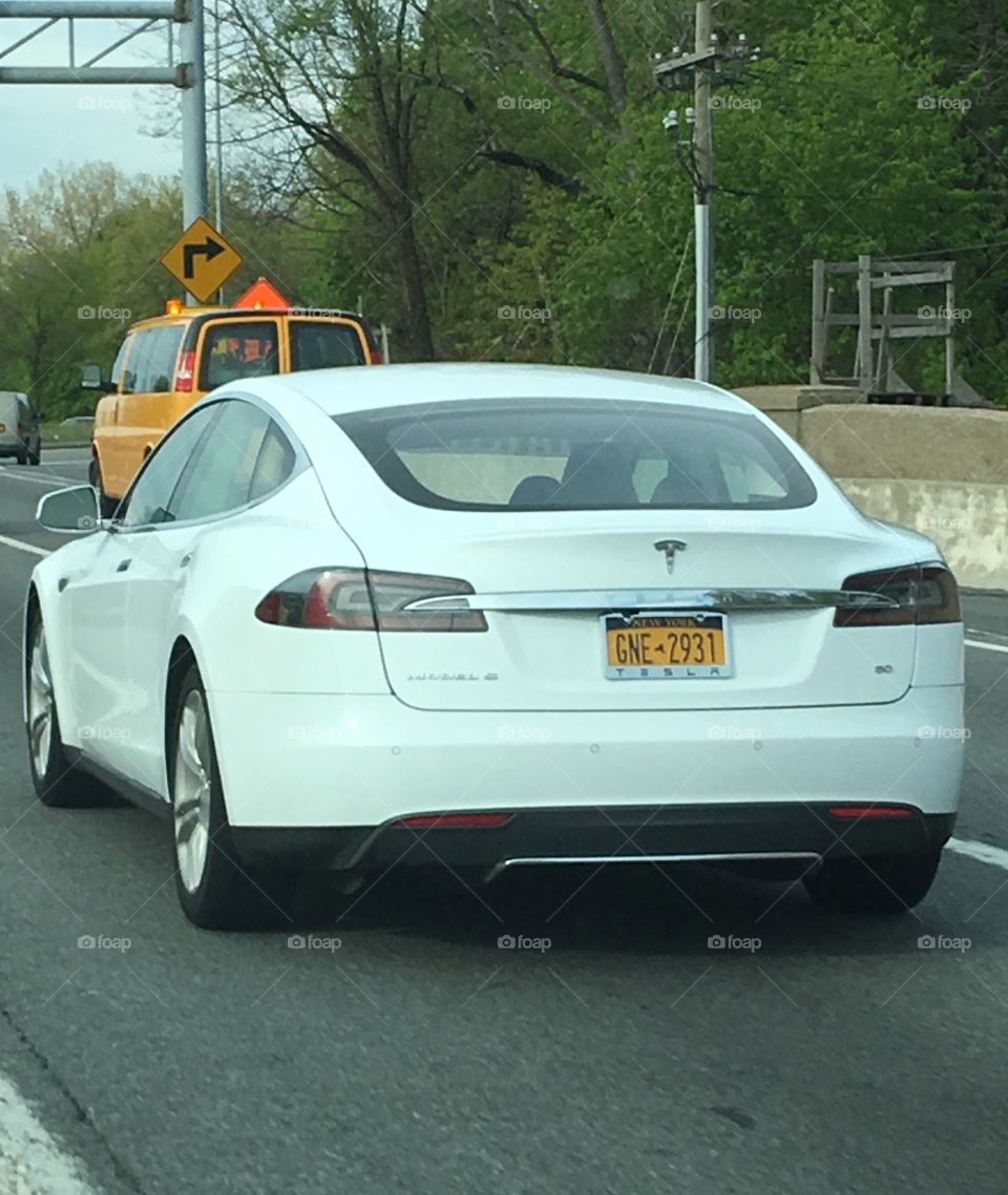 Tesla, white color, close up driving on road!