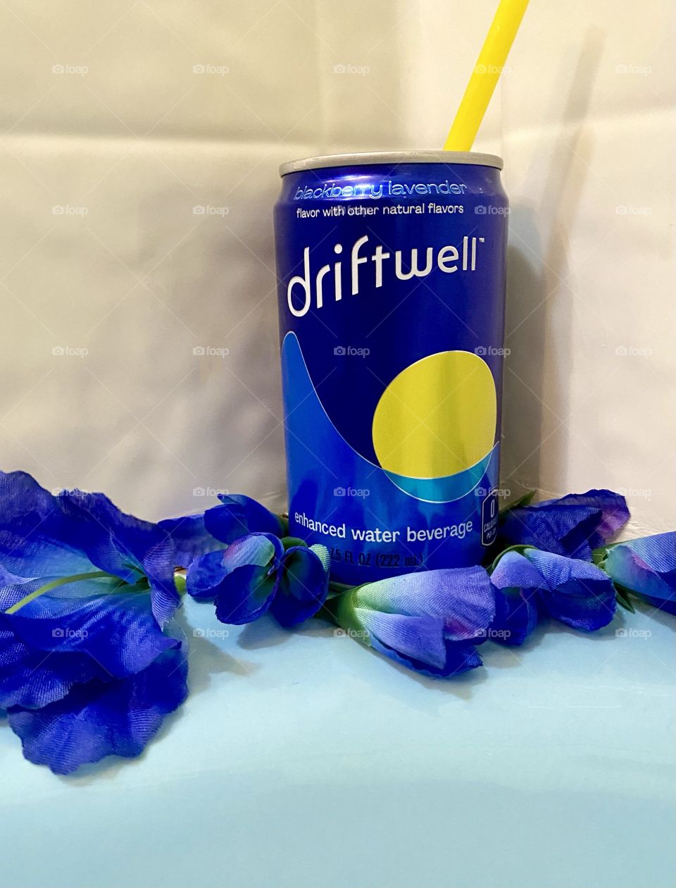 Driftwell surrounded with dark blue flowers on the side of a blue bath tub 