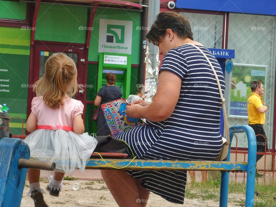 mother sits with her daughter on a bench