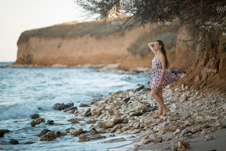 Portrait of beautiful young woman near the sea at sunset