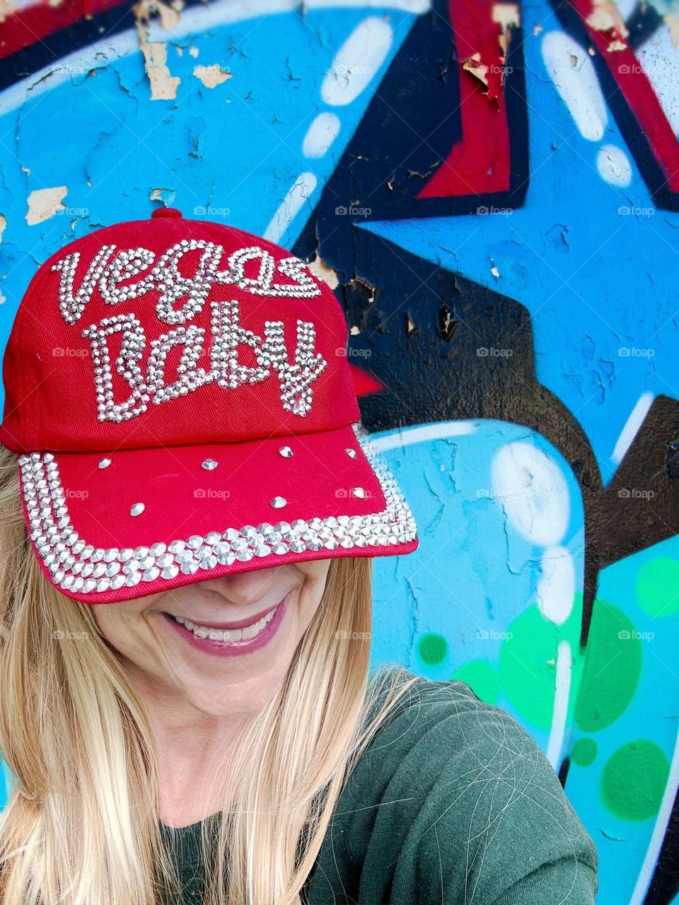 Lady in a-red hat in front of a graffiti wall.