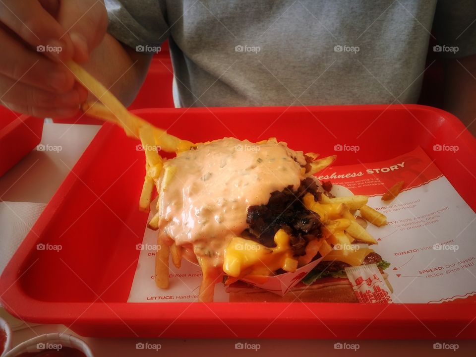 A man eating animal fries from In-N-Out burger french fries grilled onion cheese and sauce