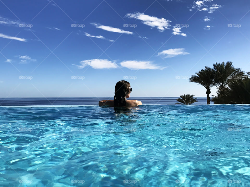 Woman in blue swimming pool during tropical vacation 