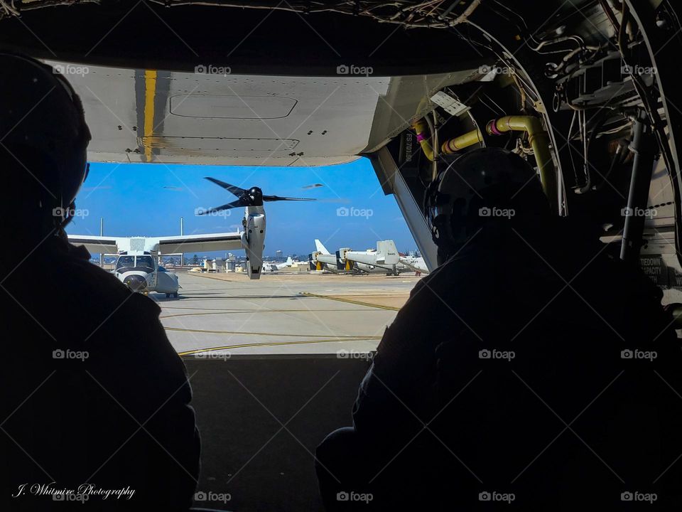 A Osprey is photographed through an open rear door during taxi