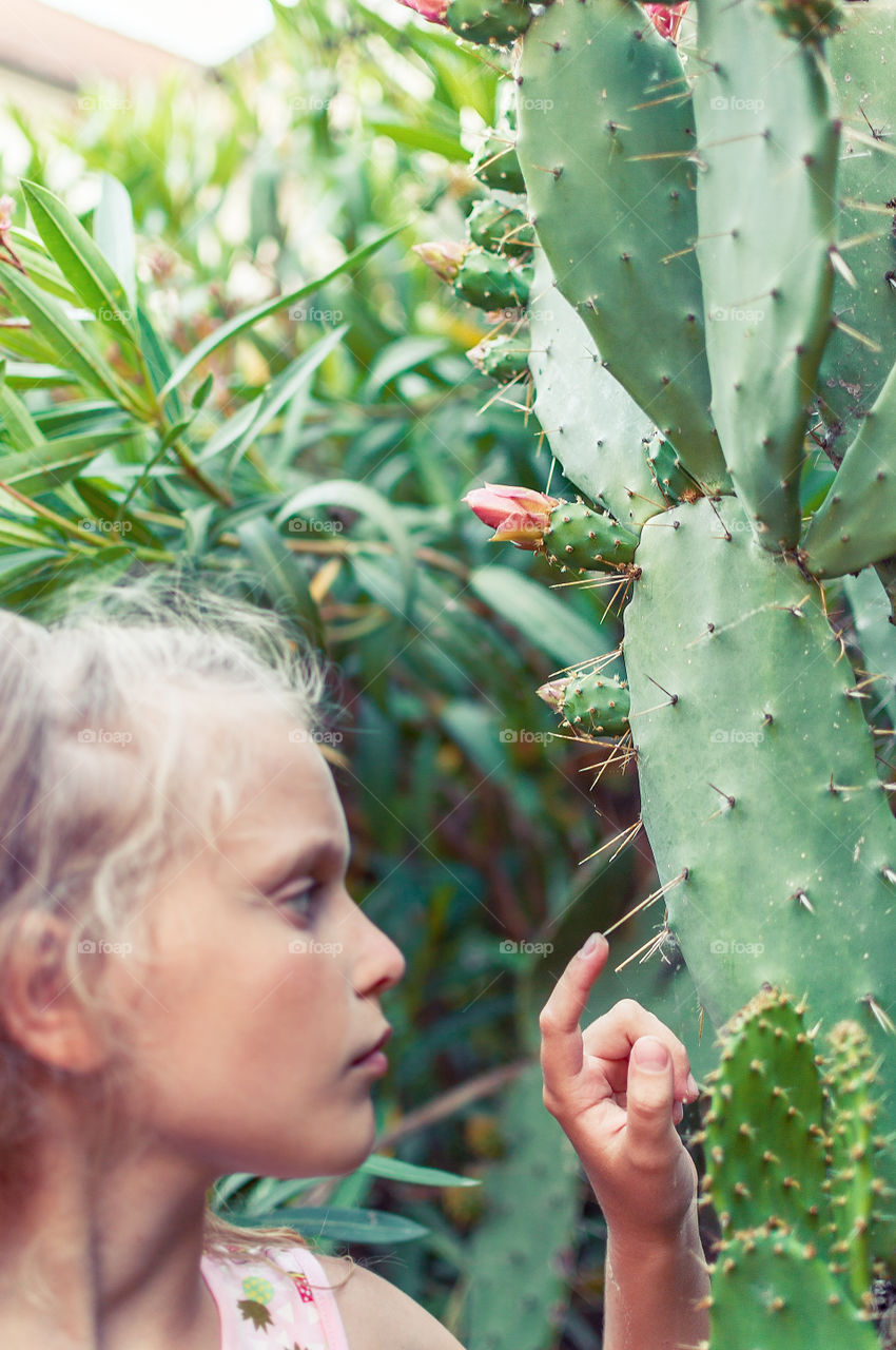 Girl is touching sharp cactus