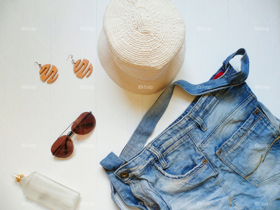 denim bag, hat sunglasses, eau de toilette and earrings on a white background