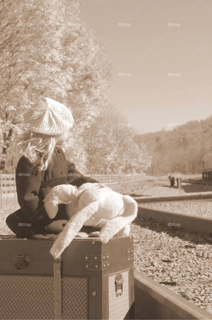 Old time feel photo of young girl looking down the train tracks. 