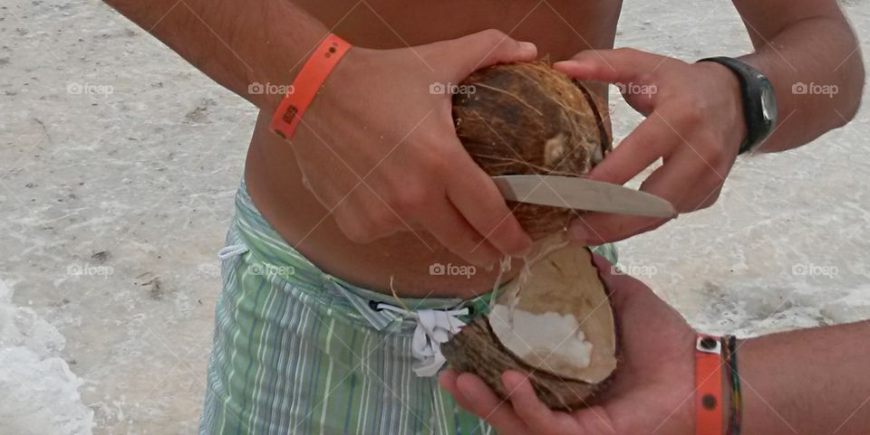 particular view of hand holding and opening a fresh cononut