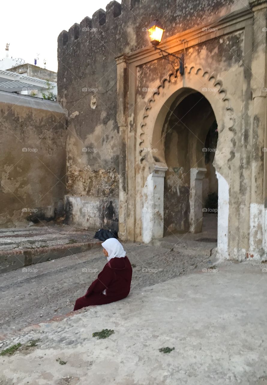 A woman sits near an arch in Tangier