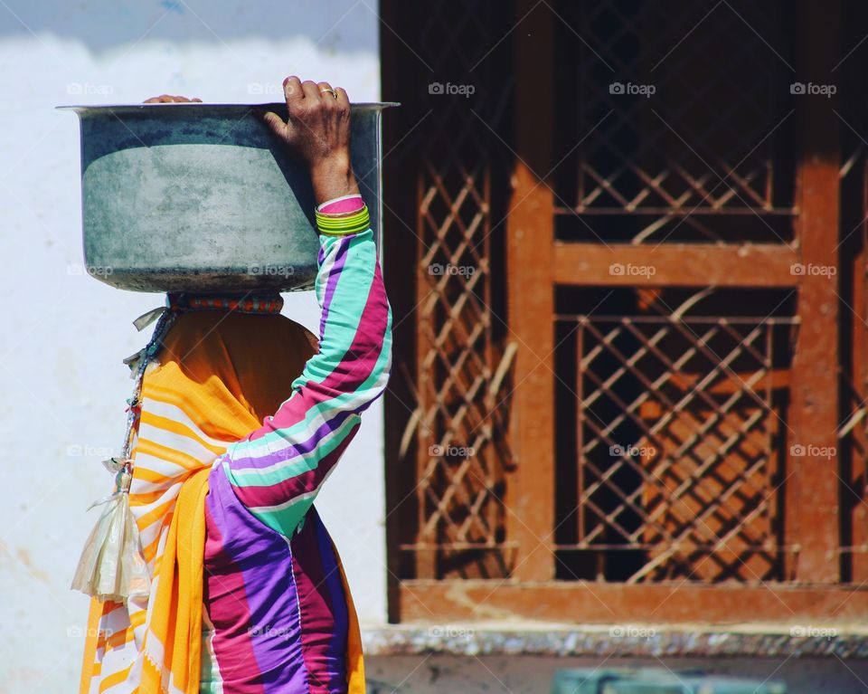A woman returning home after fetching water in India.