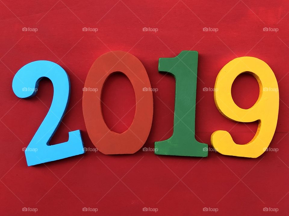 Happy New Year 2019 with colored wooden letters over a red colored board