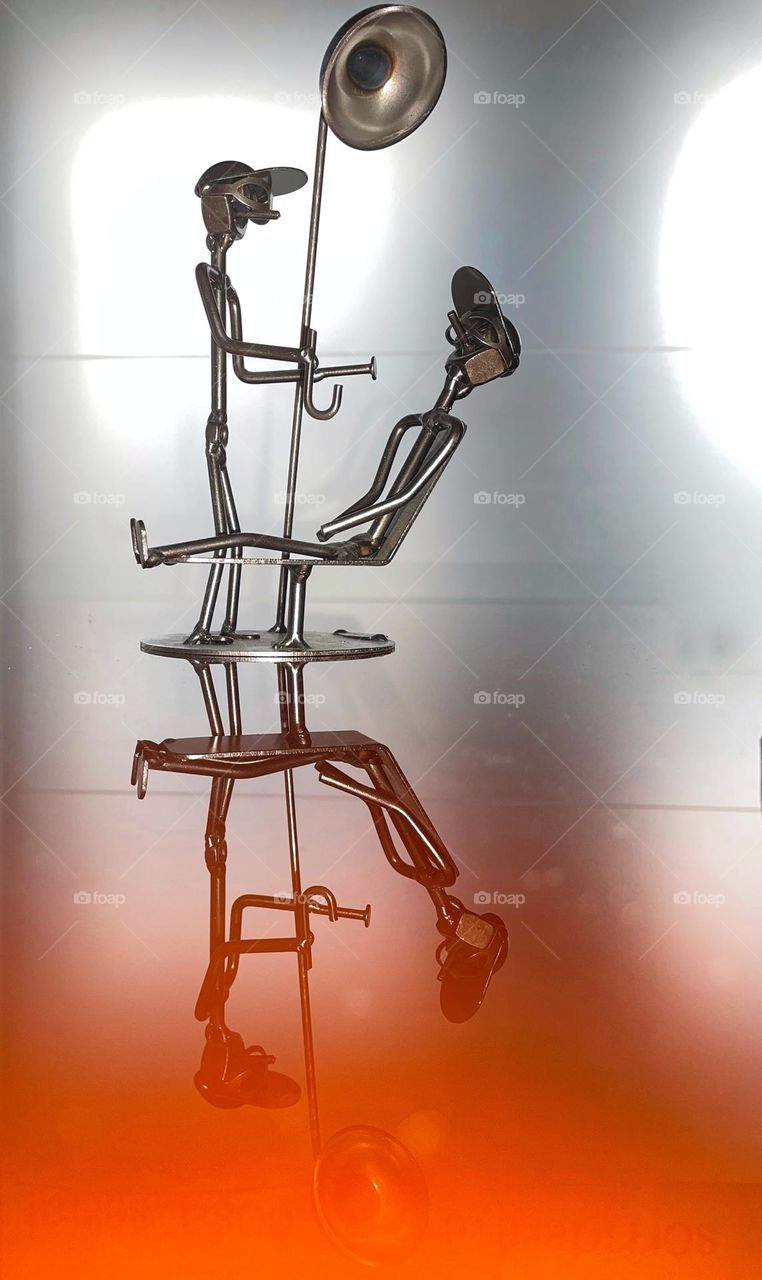 metal sculpture of the dentist's professional chair with patient reflected on a glass table