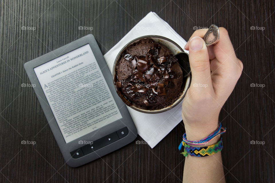 Girl eats chocolate dessert and read e-books