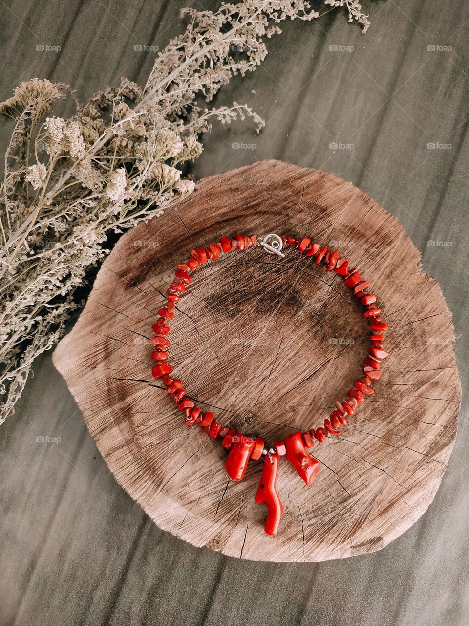 Red irregular beaded coral necklace on wooden log