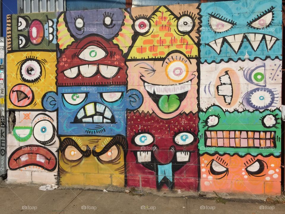 Picture of urban graffiti in Brooklyn . The picture resembles different faces with unique color and style. These are artwork done on old Brooklyn building factories .the faces look like extraterrestrial beings.