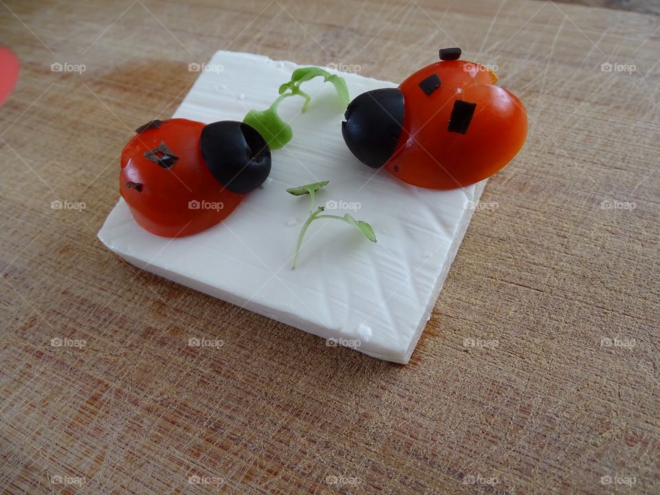 Ladybugs made of tomato and olives on feta cheese