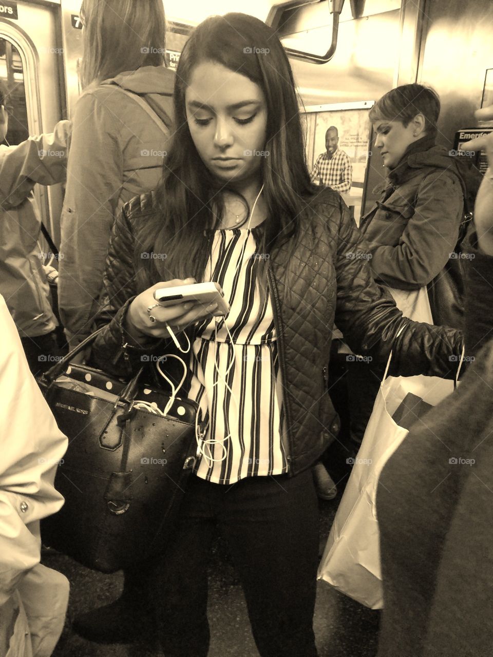 Girl Riding Subway in NYC Looking at her Phone. Sepia Filter.