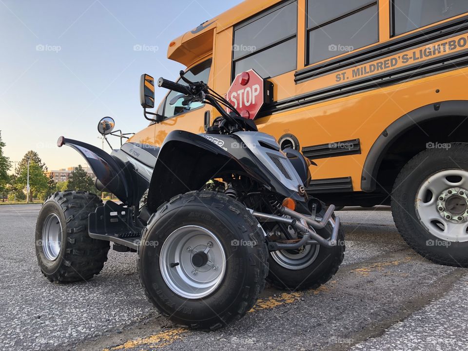 E-Ton 90cc ATV parked up against a school bus .  Beautiful and elegant driving machine, very refined in comparison to other ATVs.  Extremely fast.  100% illegal on public roads.  100% fun.