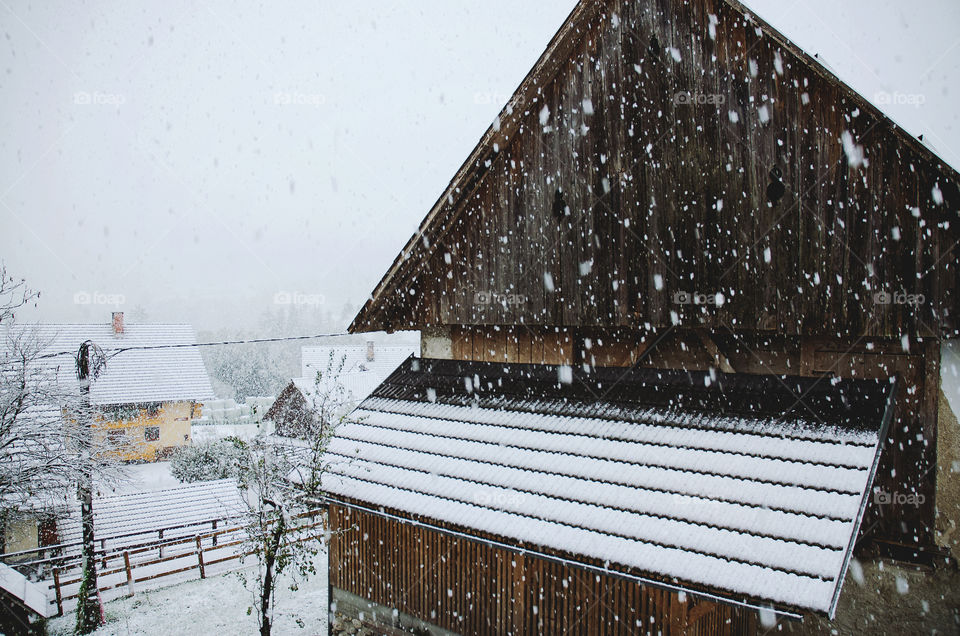 Beautiful view of the winter village with snow covered farm and road against foggy sky.