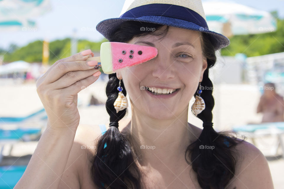 Woman at the beach holds pink ice cream and smiling, close up portrait, happy people
