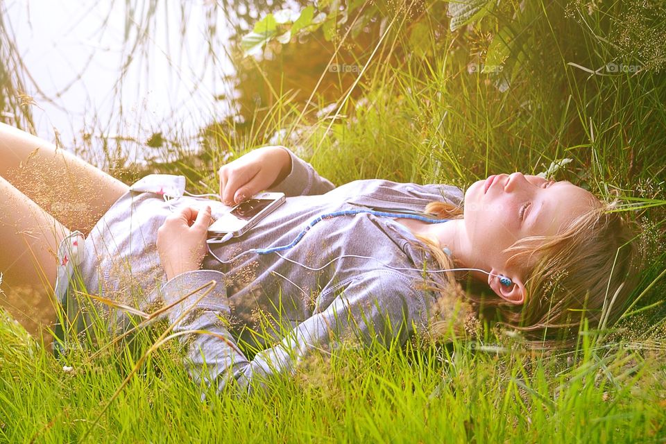 Listen to music. Girl listens to music at the lake during golden hour