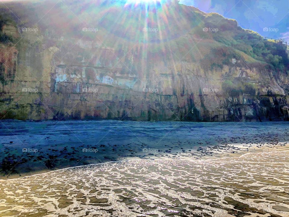 Rainbow sunbeams sunshine beach cliffs bluff waves sand