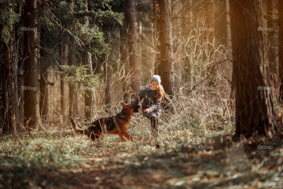 Girl walking with German shepherd puppy in a spring forest 