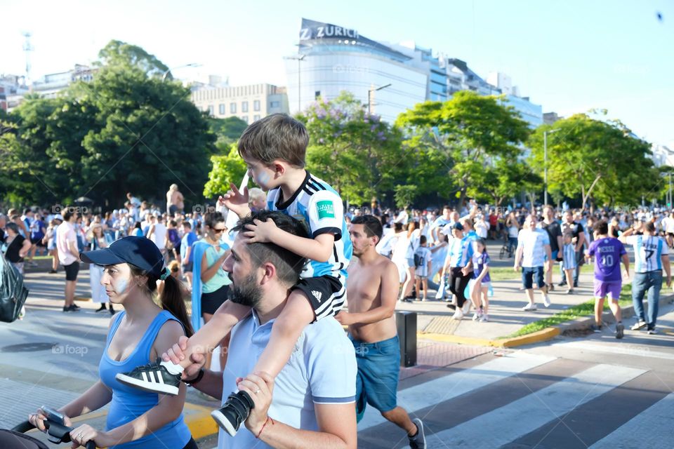 Buenos Aires - 18.12.2022: A family of football fans with children in t-shirts of the national team of Argentina walks down the street
