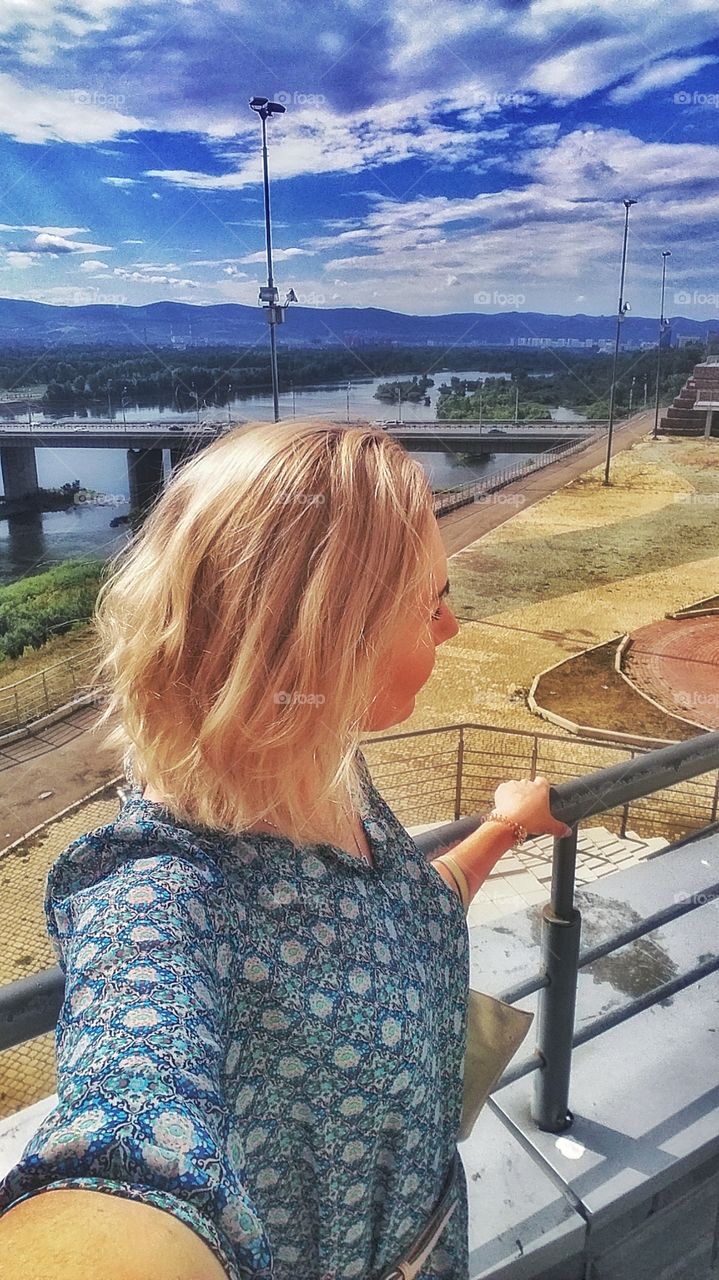 девушка блондинка на фоне городского моста